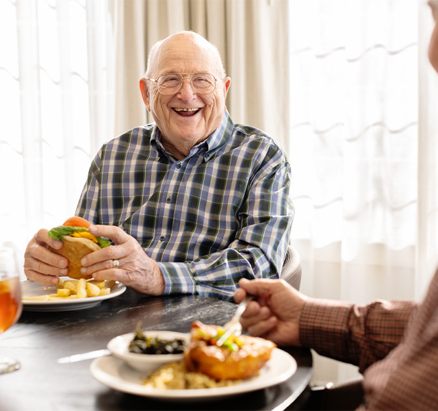 Man eating a burger and smiling at Broadway Cityview