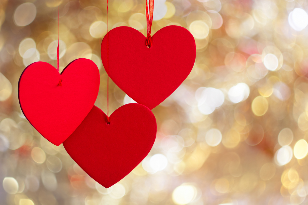 Three red hearts on an illuminated background.