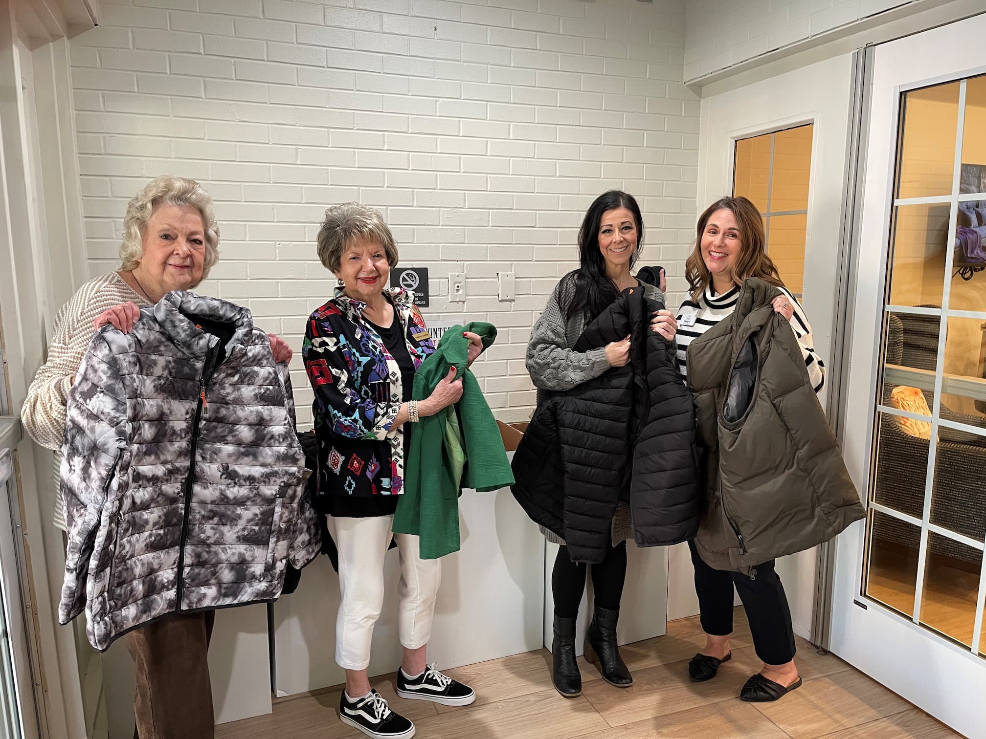 Ladies hold up donated coats from Broadway Cityview coat drive