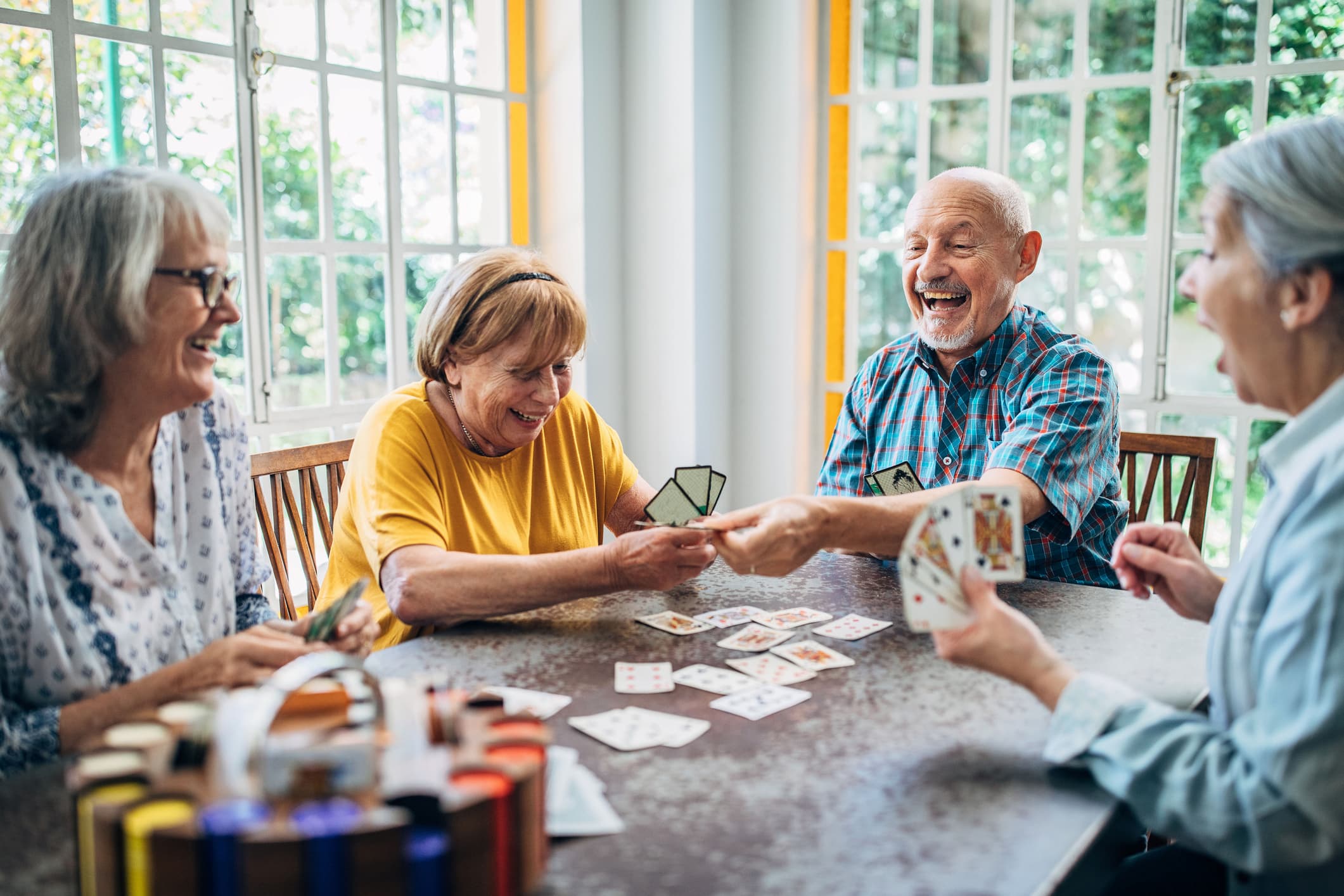Broadway_Beginner Bridge-Event Image_01-29-2026 Senior friends sitting around a table playing cards and laughing
