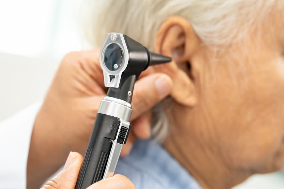 Doctor checking senior man's ear