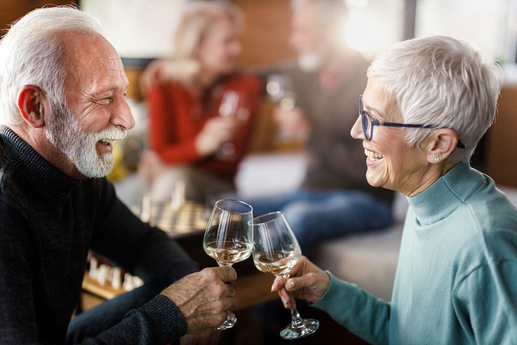senior woman and senior man toast wine glasses at social event