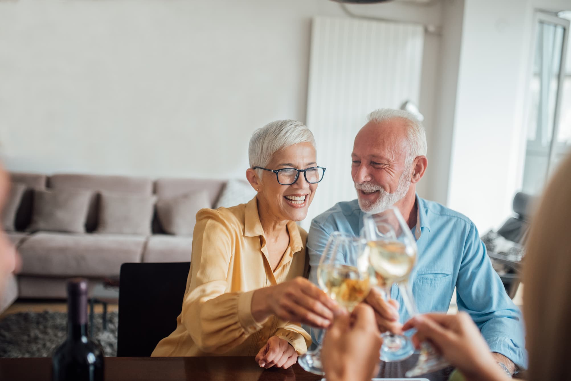 senior couple smiling and toasting wine glasses with friends