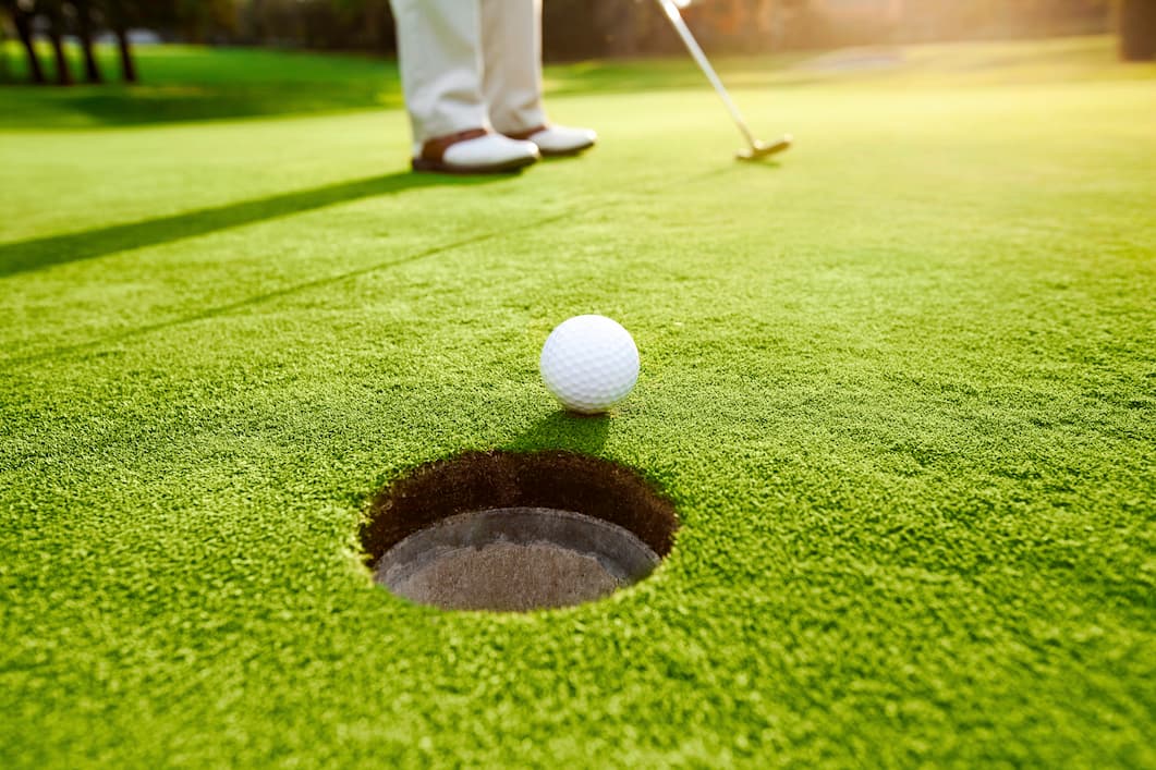 close up of golf ball rolling into hole