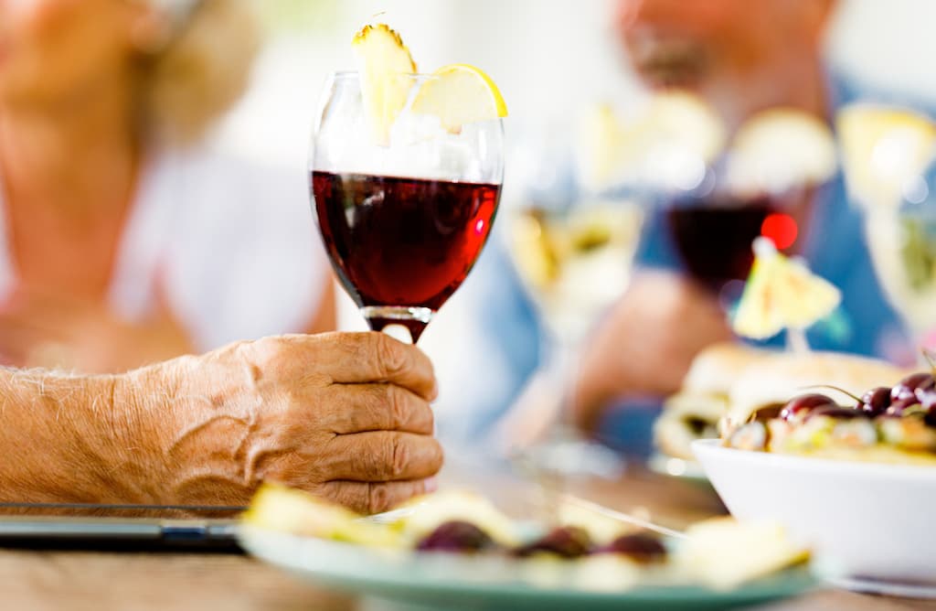 close up of senior holding glass of wine with fruit garnish