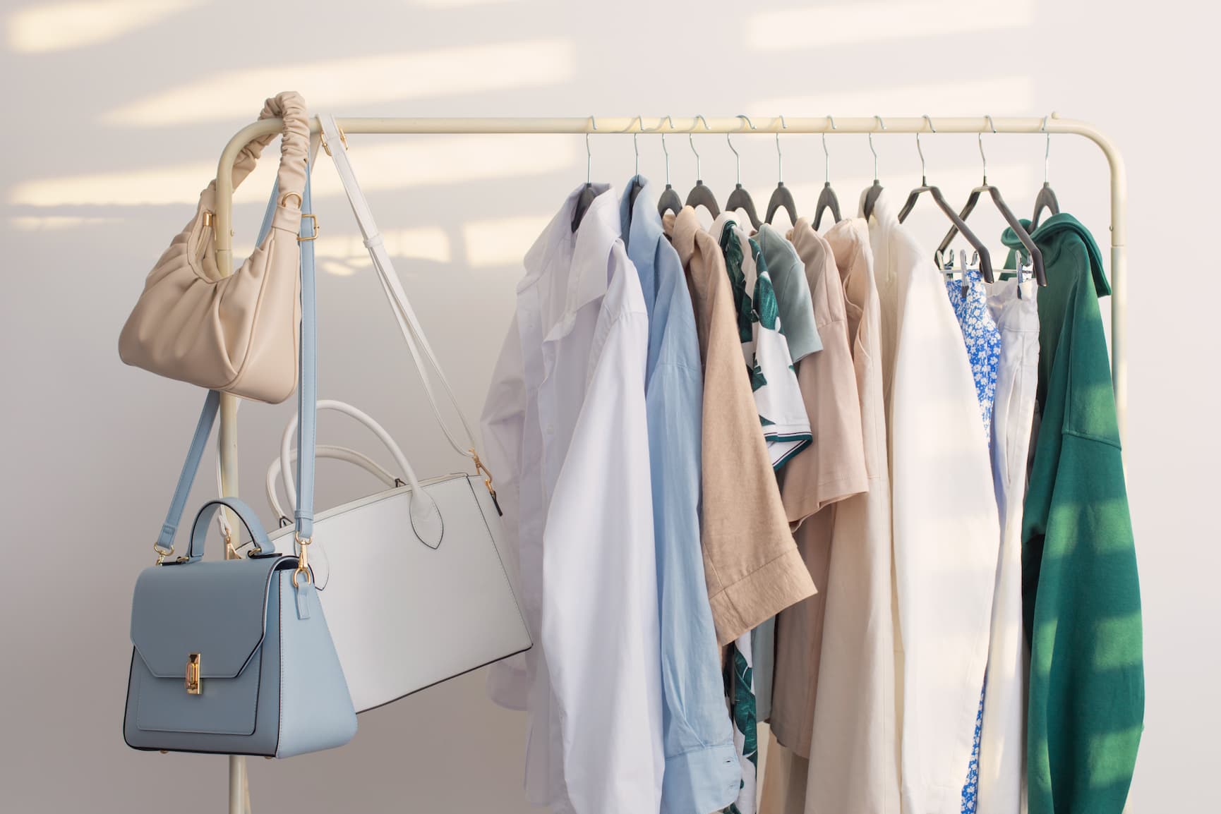 Clothing and bags on a rack in a sunlit room.