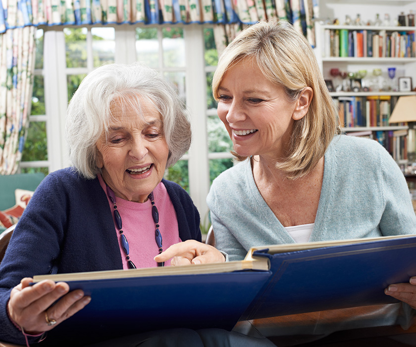 Senior woman reading book with adult daughter